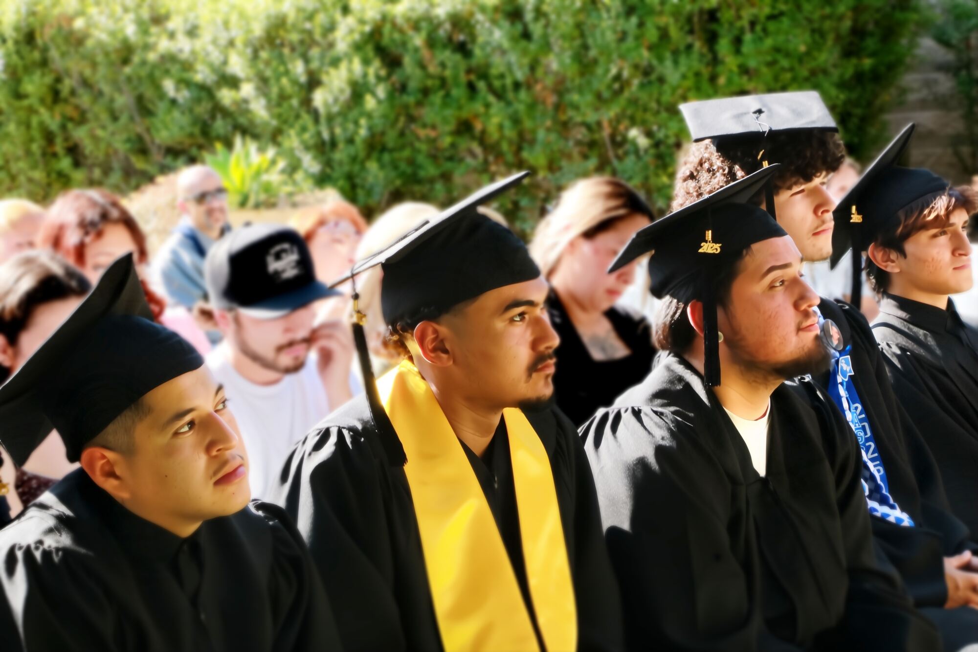 Corpsmembers in caps and gowns at an outdoor graduation