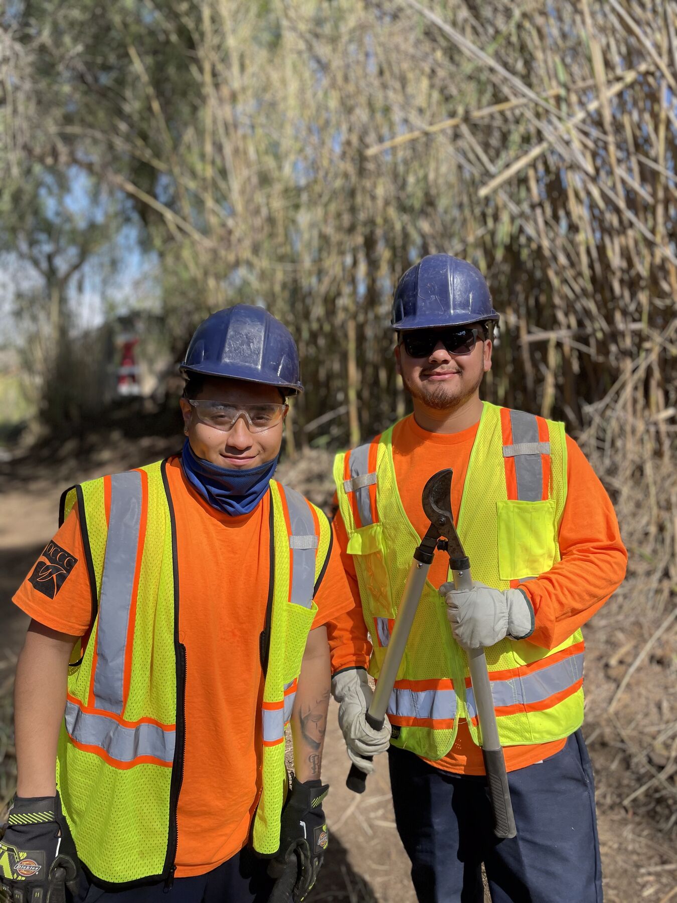Two smiling corpsmembers in hard hats and safety vests